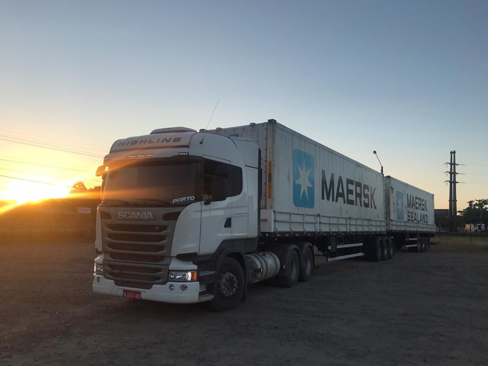 Caminhão da Porto Sul transportando containers marítimos ao pôr do sol